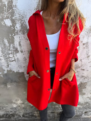 Donna con cappotto rosso elegante, indossa top bianco e jeans. Moda autunnale, stile casual chic. Sfondo muro bianco.