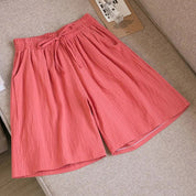 Pantaloncini donna rosa in cotone, elastico in vita con laccio, stile casual estivo, su divano beige. Abbigliamento comodo e alla moda.