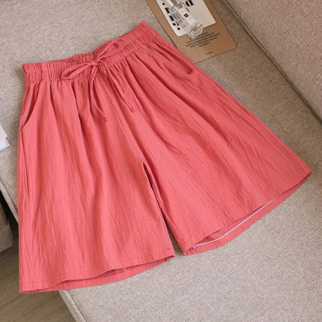Pantaloncini donna rosa in cotone, elastico in vita con laccio, stile casual estivo, su divano beige. Abbigliamento comodo e alla moda.