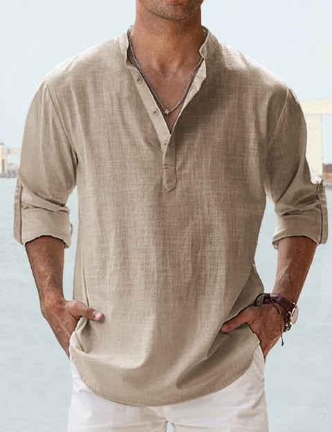 Camicia uomo beige in lino, maniche lunghe arrotolate, colletto alla coreana, abbinata a pantaloni bianchi. Stile casual estivo elegante.