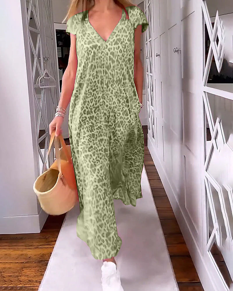 Donna con abito lungo leopardato verde, borsa di paglia e scarpe bianche, cammina in corridoio moderno. Moda estiva, abbigliamento casual chic.