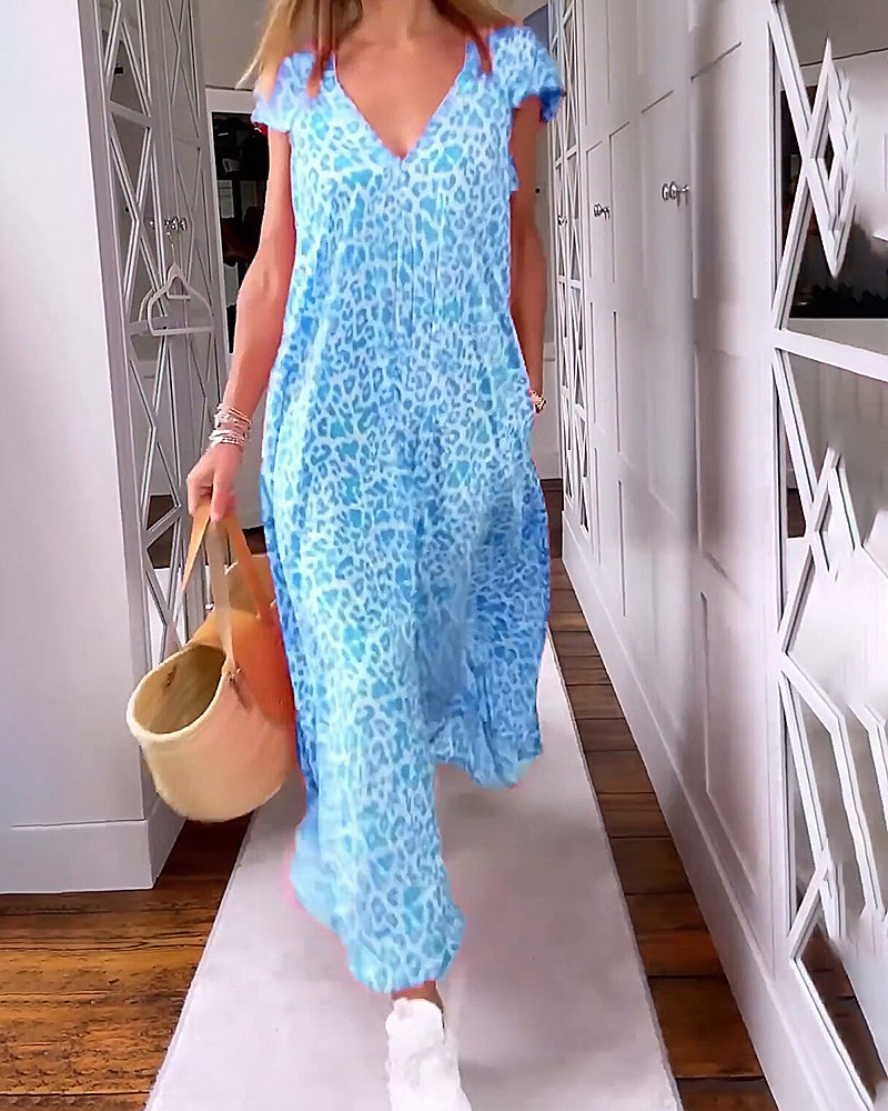 Donna con abito lungo azzurro leopardato, borsa di paglia e scarpe bianche. Moda estiva, abbigliamento casual elegante.