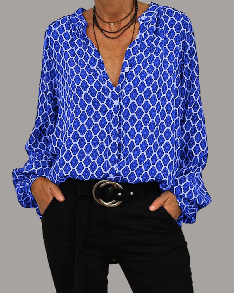 Camicia donna blu a fantasia geometrica, maniche lunghe, scollo a V, abbinata a pantaloni neri e cintura con fibbia rotonda. Moda casual elegante.