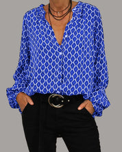 Camicia donna blu a fantasia geometrica, maniche lunghe, scollo a V, abbinata a pantaloni neri e cintura con fibbia rotonda. Moda casual elegante.