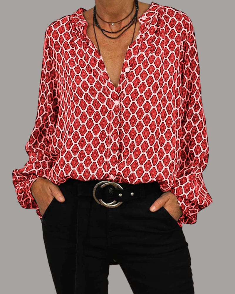 Camicia donna rossa a fantasia geometrica, maniche lunghe, scollo a V, abbinata a pantaloni neri e cintura con fibbia. Moda casual elegante.