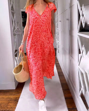 Abito lungo estivo donna, stampa leopardata rosa, scollo a V, maniche corte, abbinato a borsa di paglia e scarpe bianche, moda casual elegante.
