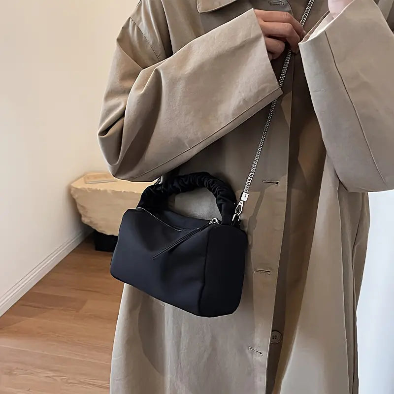 Cappotto beige elegante con borsa a tracolla nera in tessuto, design moderno, ideale per moda autunnale. Accessorio chic per look casual.