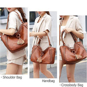 Borsa a spalla in pelle marrone con nappine, indossata da donna in abito chiaro. Design versatile: borsa a mano e tracolla. Elegante e pratica.
