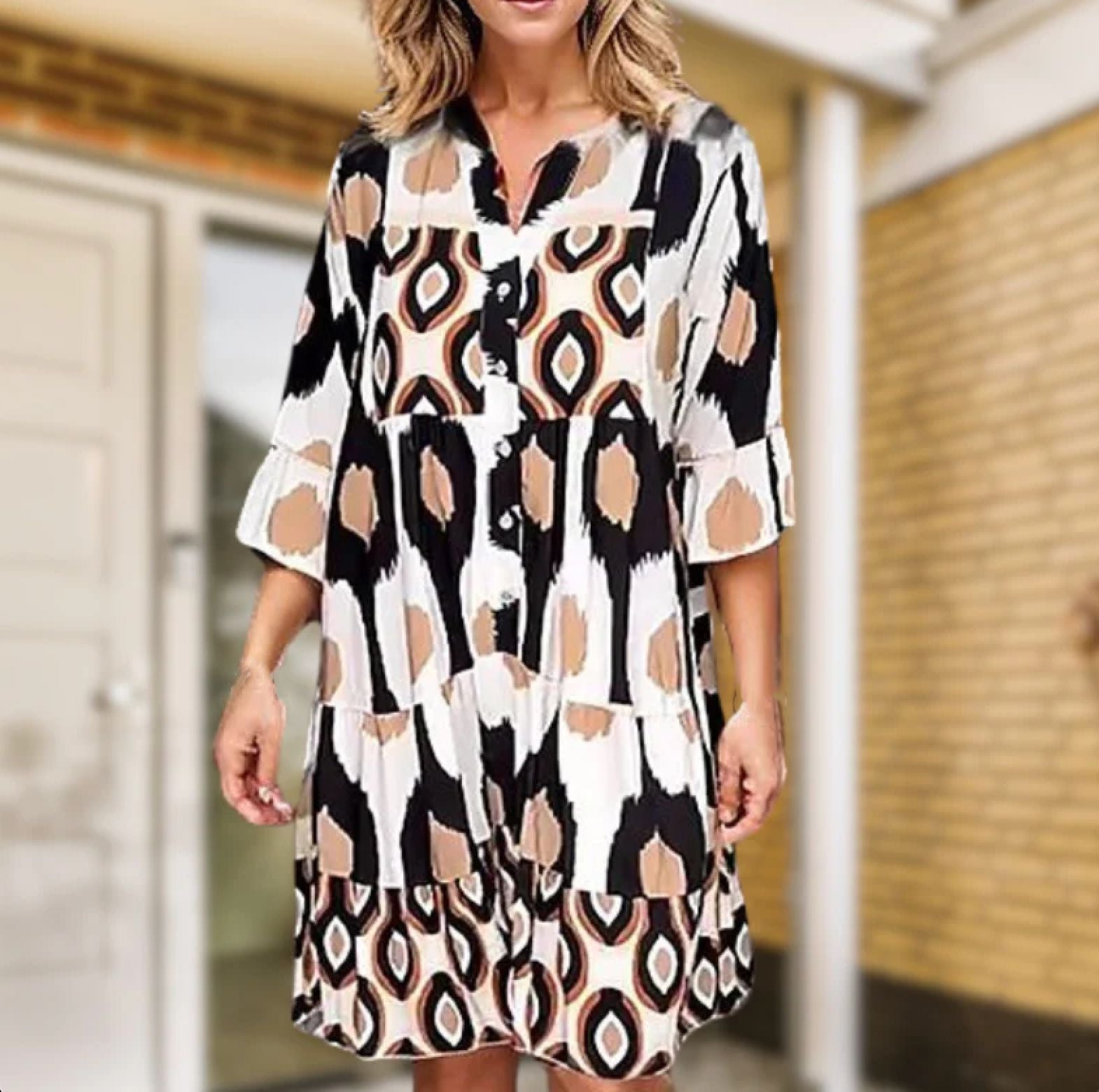 Abito estivo donna con stampa geometrica multicolore, maniche a tre quarti, scollo a V, sfondo esterno. Moda casual, abbigliamento femminile trendy.
