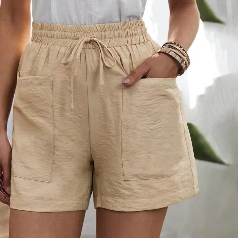 Shorts beige da donna con tasche frontali, elastico in vita e laccio, indossati con maglietta bianca. Stile casual estivo.