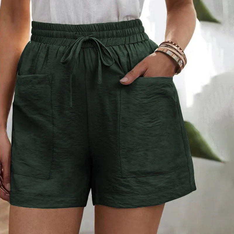 Shorts verdi da donna con tasche frontali, elastico in vita e laccio, indossati con top bianco. Stile casual estivo, moda femminile.