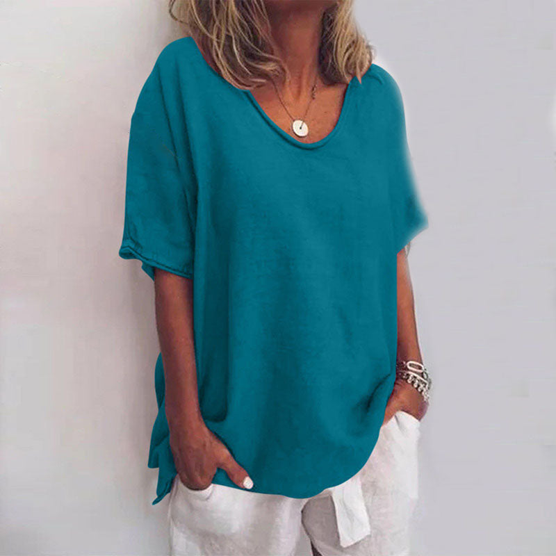 Donna con maglietta turchese casual, maniche corte, scollo rotondo, abbinata a pantaloni bianchi. Stile estivo, moda femminile, abbigliamento casual.