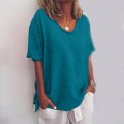 Donna con maglietta turchese casual, maniche corte, scollo rotondo, abbinata a pantaloni bianchi. Stile estivo, moda femminile, abbigliamento casual.