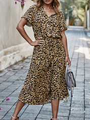 Donna con abito lungo leopardato, strada lastricata, borsa grigia, moda estiva, stile casual chic, tendenza abbigliamento femminile.