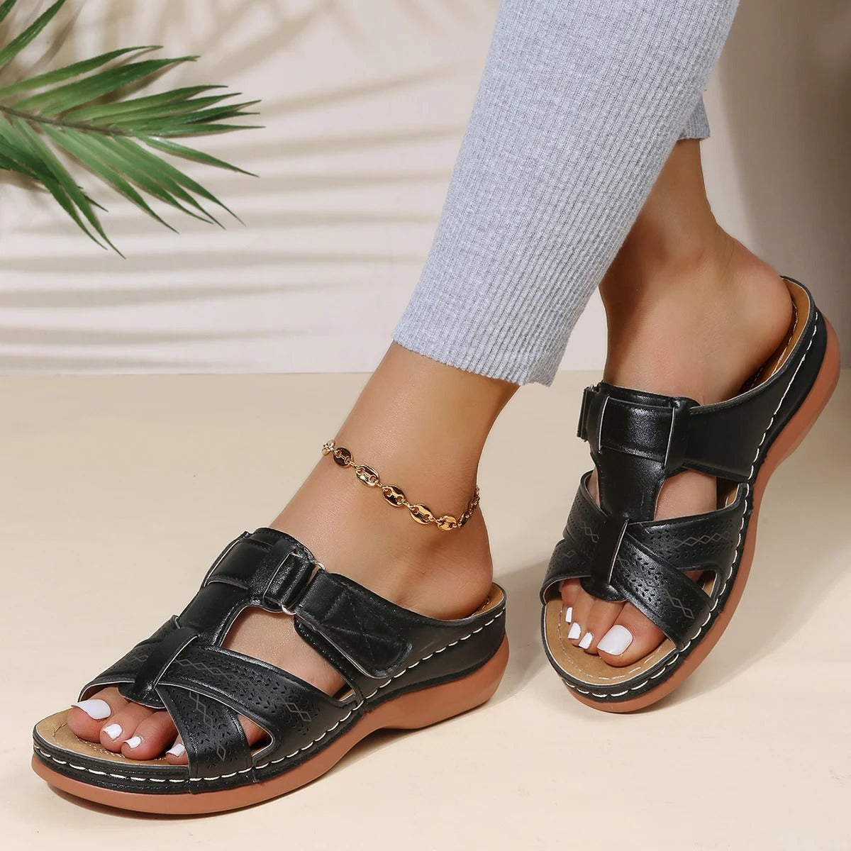 Sandali donna neri in pelle con fibbie, suola comoda, indossati con pantaloni grigi. Scarpe estive eleganti e casual.