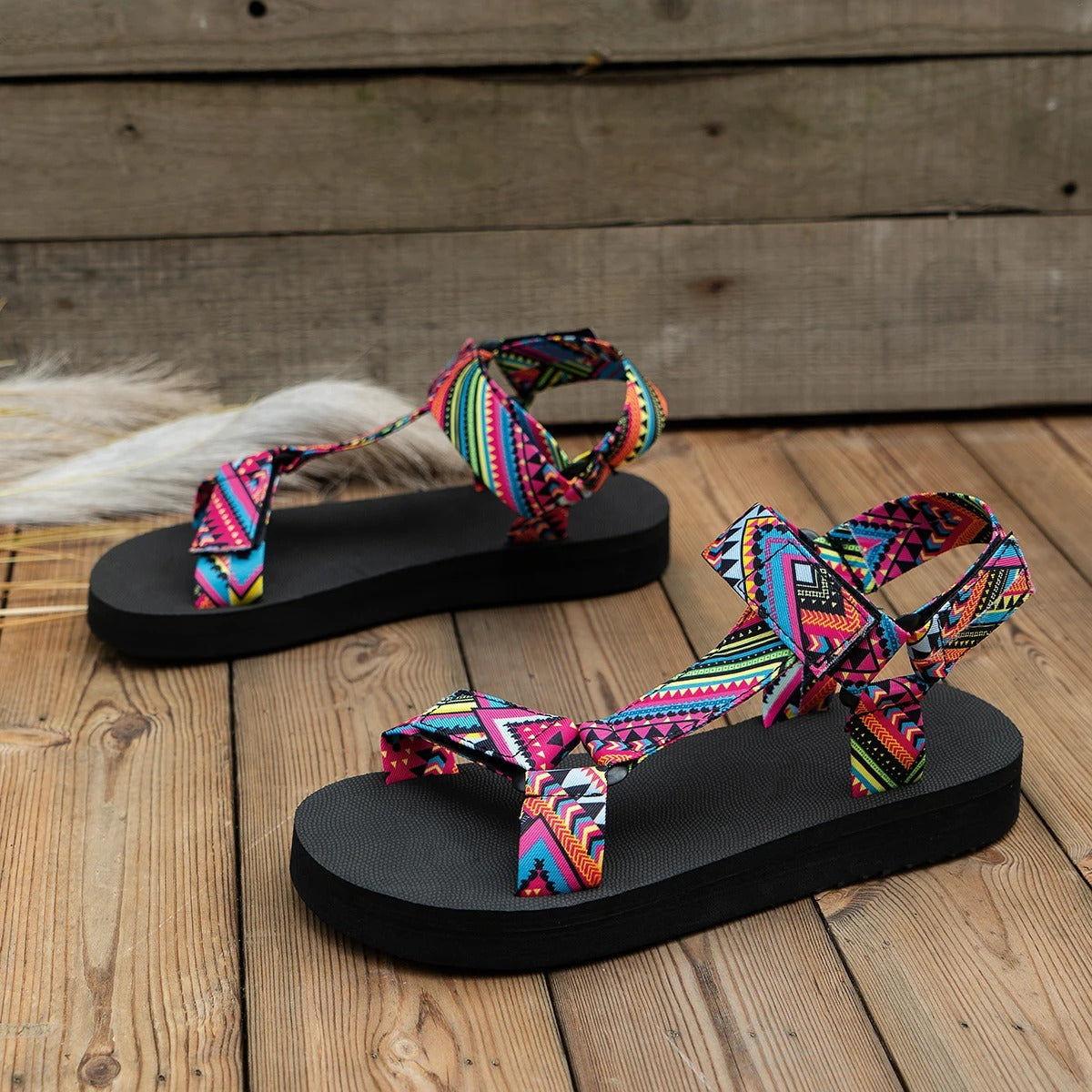Sandali estivi da donna con suola nera e cinturini multicolore a motivi geometrici, ideali per look casual e vacanze.