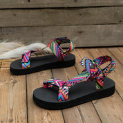 Sandali estivi da donna con suola nera e cinturini multicolore a motivi geometrici, ideali per look casual e vacanze.