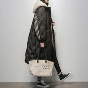 Donna con cappotto lungo nero trapuntato, cappuccio beige, borsa a mano beige "Bello Paris", scarpe Converse nere. Moda invernale casual.