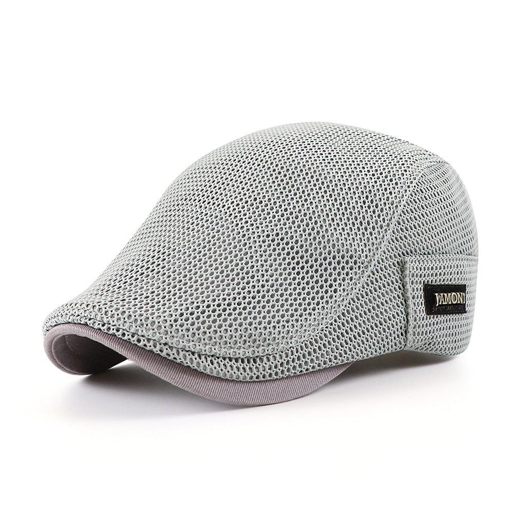 Cappello piatto grigio in rete traspirante, stile estivo, con etichetta laterale. Accessorio moda uomo, leggero e confortevole.