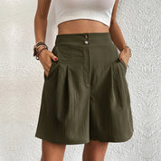 Donna con pantaloncini a vita alta verde oliva, tasche laterali, bottoni decorativi, top bianco. Moda estiva casual, abbigliamento femminile trendy.