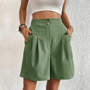 Donna con pantaloncini verdi a vita alta, tasche laterali, abbinati a top bianco. Moda estiva casual, abbigliamento femminile trendy.