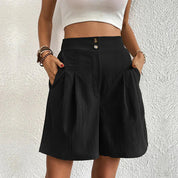 Donna con pantaloncini neri a vita alta, top bianco senza maniche. Moda estiva casual, abbigliamento femminile elegante.