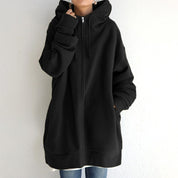 Felpa nera oversize con cappuccio, zip frontale e tasche, indossata da una persona. Stile casual, ideale per moda autunnale e invernale.