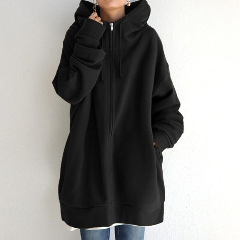 Felpa nera oversize con cappuccio, zip frontale e tasche, indossata da una persona. Stile casual, ideale per moda autunnale e invernale.