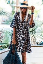Donna con abito leopardato, cappello a tesa larga e occhiali da sole, tiene una borsa trapuntata nera. Moda estiva, stile casual chic.