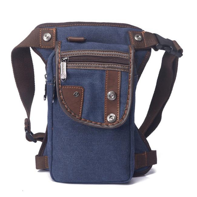 Marsupio a tracolla in tela blu con dettagli in pelle marrone, tasche multiple con cerniera, design unisex, ideale per viaggi e attività all'aperto.