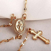 Collana rosario in oro con croce e medaglia della Madonna, dettagli raffinati, gioiello religioso elegante, accessorio spirituale di tendenza.