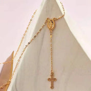 Collana rosario in oro con croce e medaglia della Madonna, design elegante e raffinato, gioiello religioso per donna, accessorio moda spirituale.