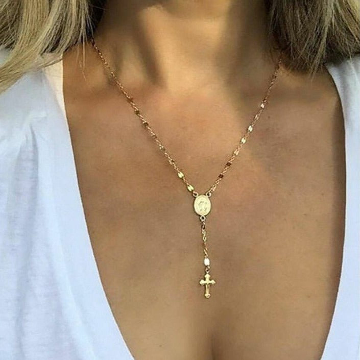 Collana in oro con ciondolo croce e medaglione su sfondo bianco. Gioielli religiosi eleganti, accessori moda donna, stile classico.