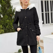 Giacca parka donna nera con cappuccio in pelliccia sintetica bianca, chiusura a bottoni, tasche frontali, indossata all'aperto. Moda invernale elegante.