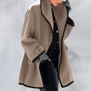Cappotto donna elegante beige con bordi neri, stile oversize, chiusura a bottone, ideale per moda invernale. Abbigliamento femminile di tendenza.