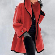 Cappotto rosso donna elegante, con bordi neri, abbinato a guanti grigi e pantaloni neri. Moda invernale, stile sofisticato.