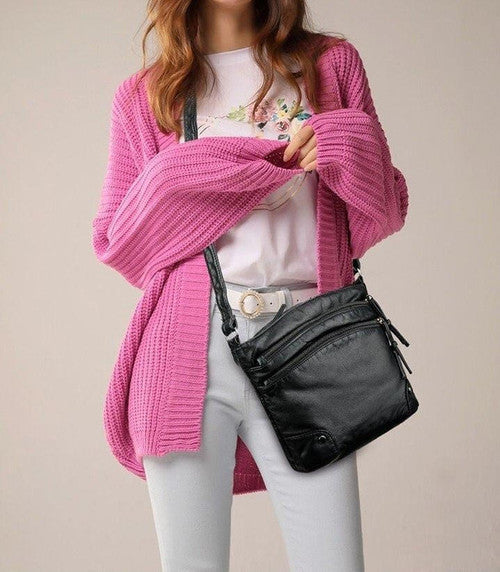 Donna con cardigan rosa, maglietta bianca floreale, jeans chiari e borsa a tracolla nera. Moda casual femminile, abbigliamento autunnale.