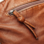 Borsa in pelle marrone con cerniera e dettaglio nodo, texture vintage. Accessorio moda elegante e resistente.