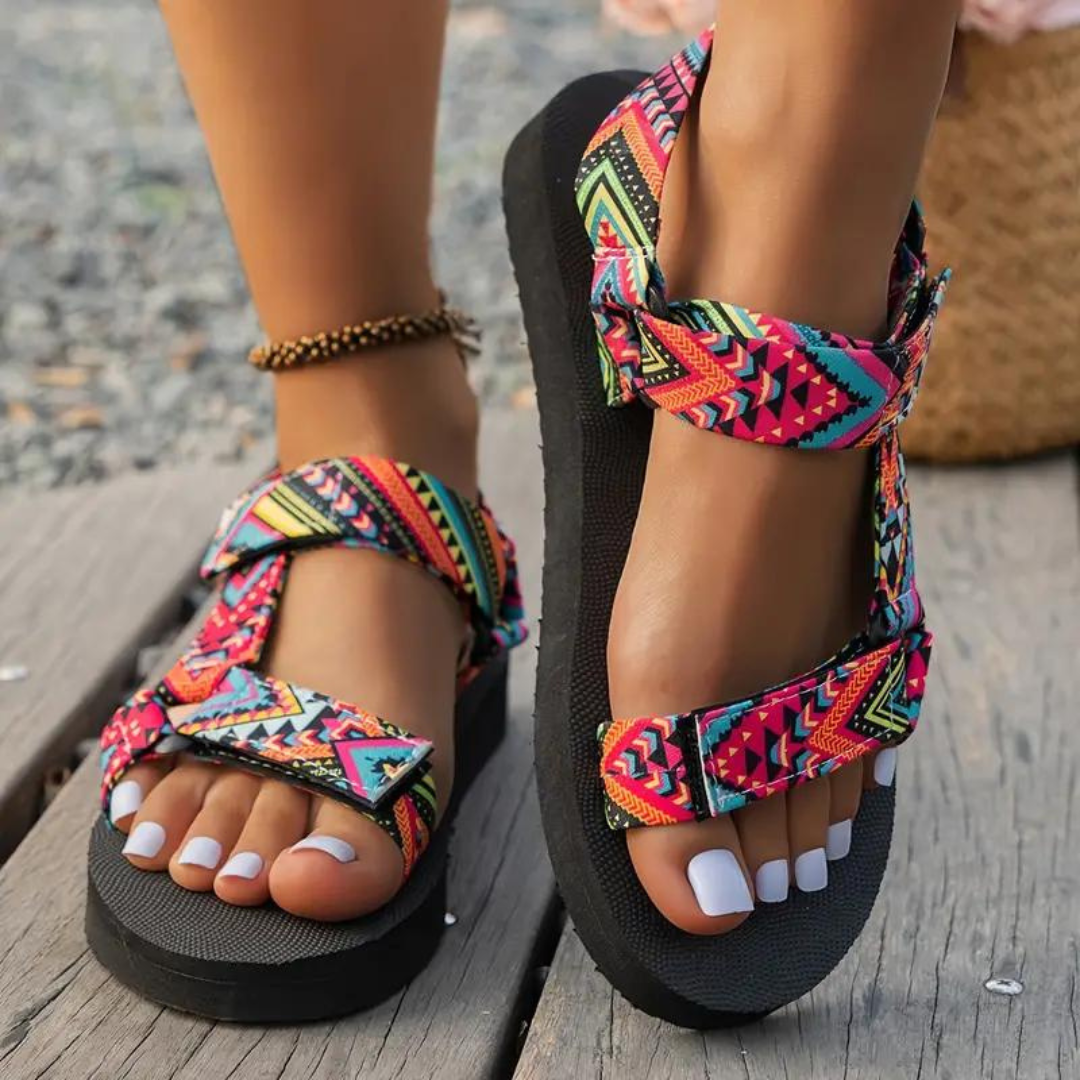 Sandali estivi da donna con cinturini regolabili multicolore, suola nera antiscivolo, indossati su passerella in legno. Perfetti per look casual.