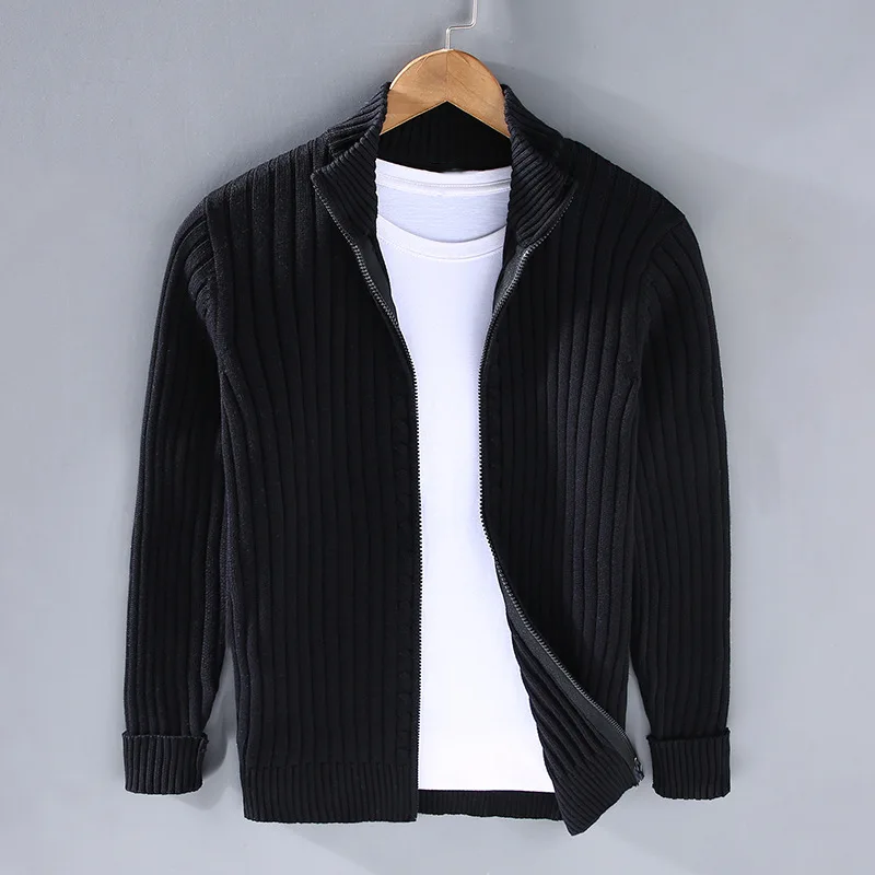 Giacca cardigan nero a coste con zip, appesa su gruccia, sopra maglietta bianca. Moda uomo, abbigliamento casual elegante.