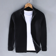 Giacca cardigan nero a coste con zip, appesa su gruccia, sopra maglietta bianca. Moda uomo, abbigliamento casual elegante.