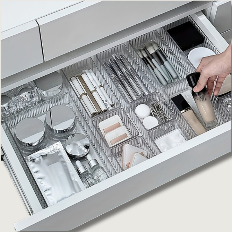 Cassetto organizzato con divisori trasparenti, contenente cosmetici, trucchi e accessori per il trucco. Soluzione di stoccaggio per bagno o camera.