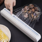 Dispenser pellicola trasparente con ciotola di vongole, mano che tira pellicola. Utensile cucina pratico per conservazione alimenti.