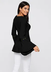 Donna con maglia nera a maniche lunghe, dettagli decorativi, abbinata a pantaloni bianchi. Moda femminile elegante, abbigliamento casual chic.