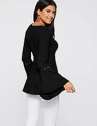 Donna con maglia nera a maniche lunghe, dettagli decorativi, abbinata a pantaloni bianchi. Moda femminile elegante, abbigliamento casual chic.