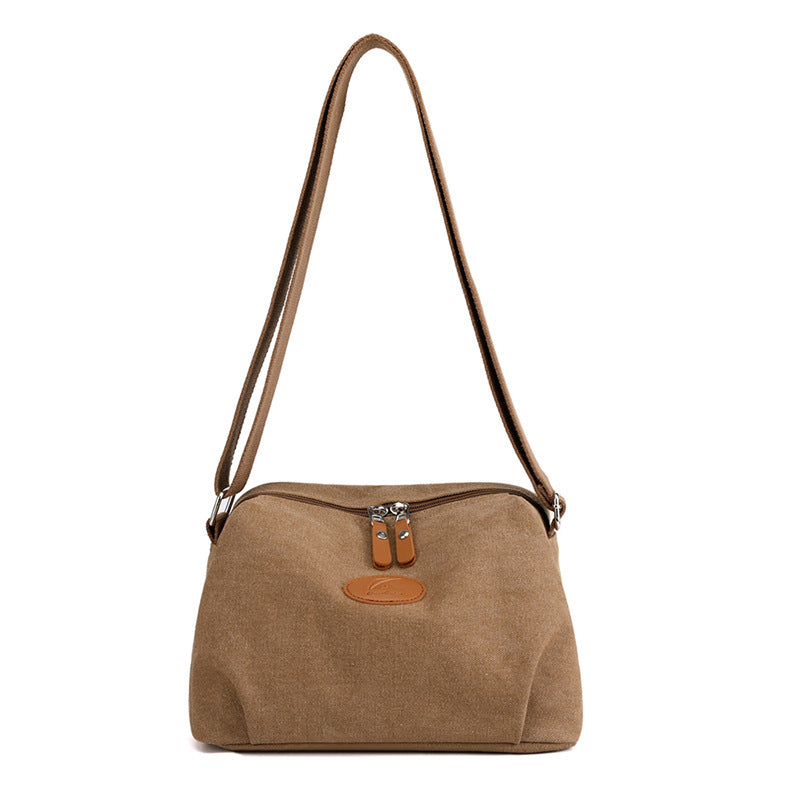 Borsa a tracolla in tela marrone con doppia cerniera e dettagli in pelle, design casual e spazioso, ideale per uso quotidiano e viaggi.