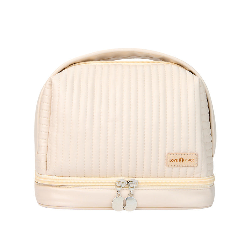 Borsa cosmetica beige trapuntata con doppia zip, manico superiore e logo "Love Peace". Ideale per viaggi, organizzazione trucco e accessori.