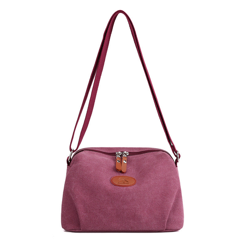 Borsa a tracolla in tessuto rosa, design elegante con chiusura a zip e dettagli in pelle marrone. Accessorio moda donna, stile casual chic.