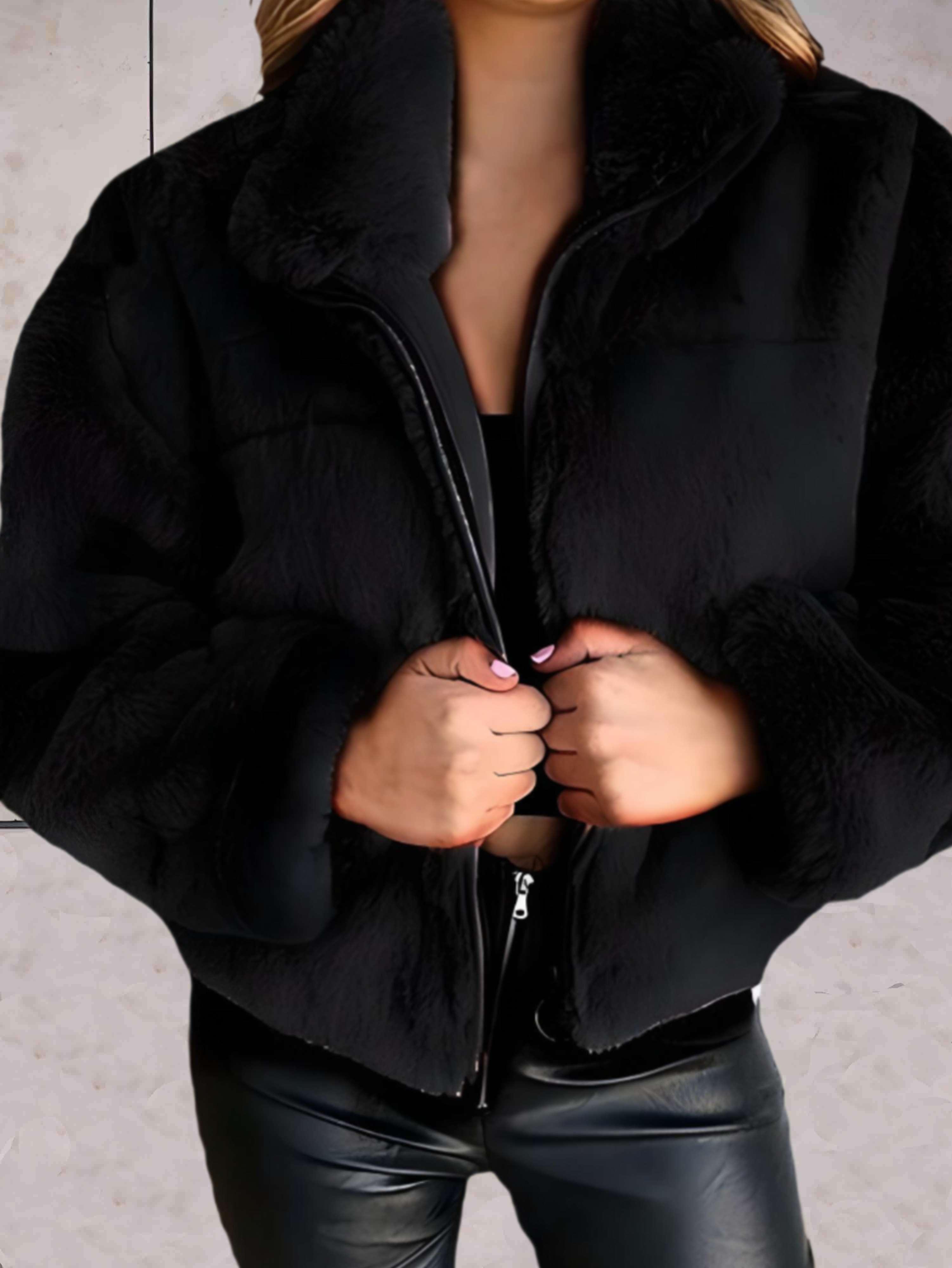 Giacca in ecopelliccia nera da donna, chiusura con zip, indossata su top nero e pantaloni in pelle. Moda invernale elegante e calda.