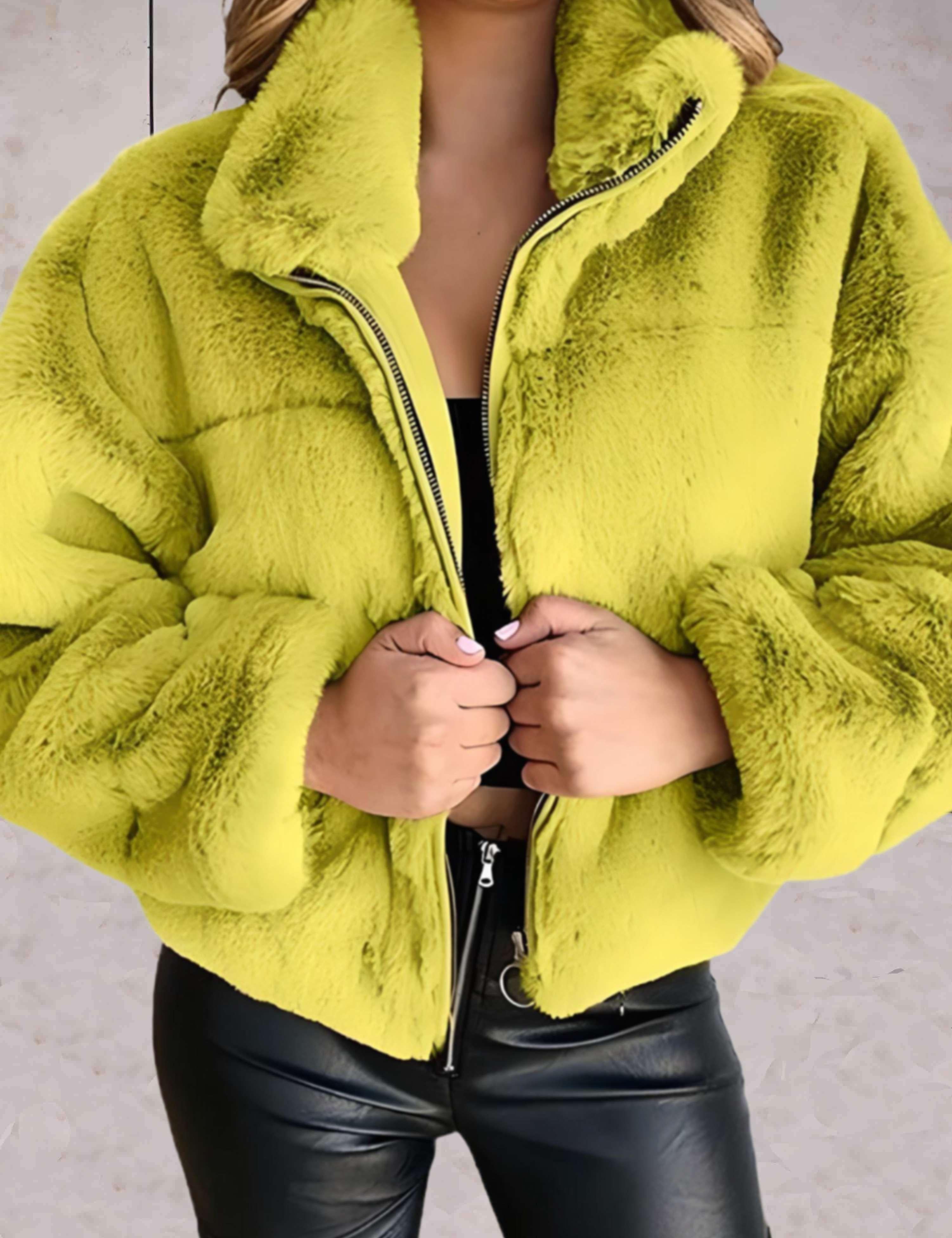 Giacca in ecopelliccia verde lime, donna, con zip frontale, indossata su top nero e pantaloni in pelle. Moda autunnale, stile casual chic.